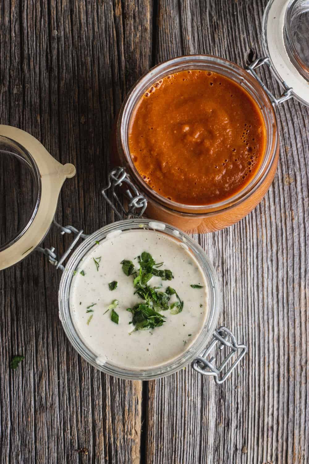 A bird's eye view of a hot sauce and ranch dressing in small jars