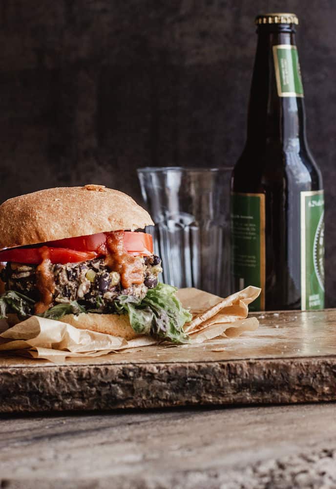 A burger on a thin wooden board with ketchup oozing our of it