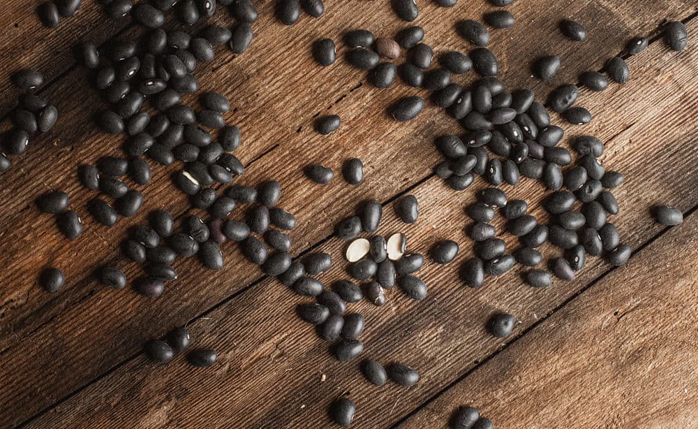Bird's eye view of dried black beans scattered on a wooden surface