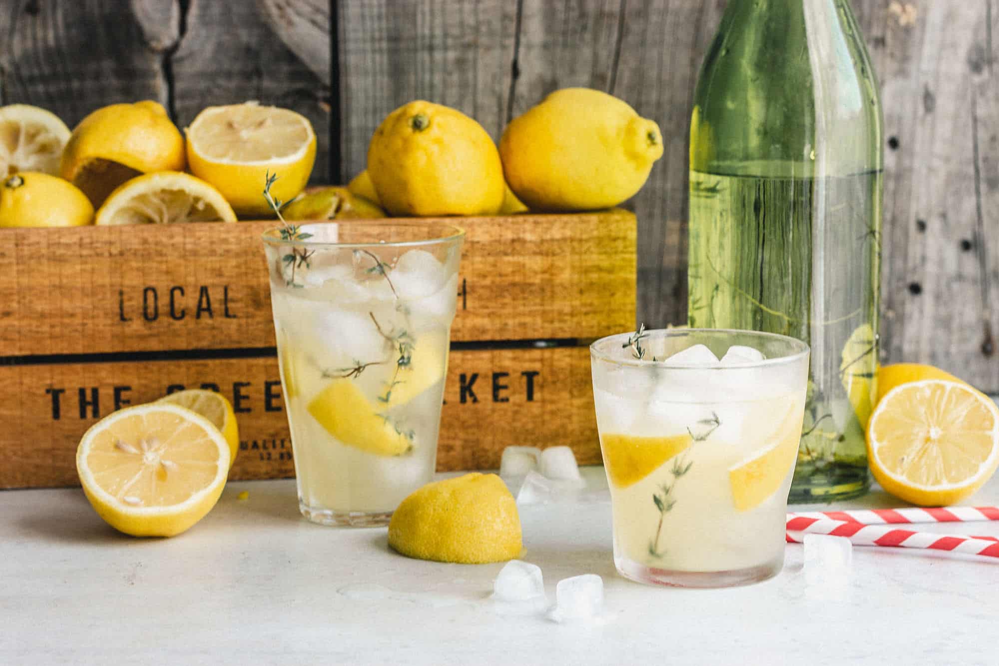 Deux verres de limonade devant un petit récipient en bois de citrons