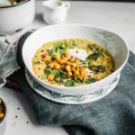 Spiced Chickpea Stew with Curry and Coconut in a white bowl on top of a blue jean napkin