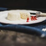 Cheese-looking round food with a on a salad plate with pomegranate arils next to it