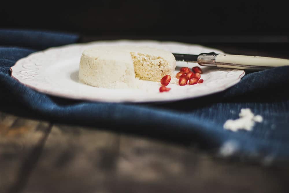 Nourriture ronde à l'aspect de fromage avec sur une assiette à salade avec des graines de grenade à côté