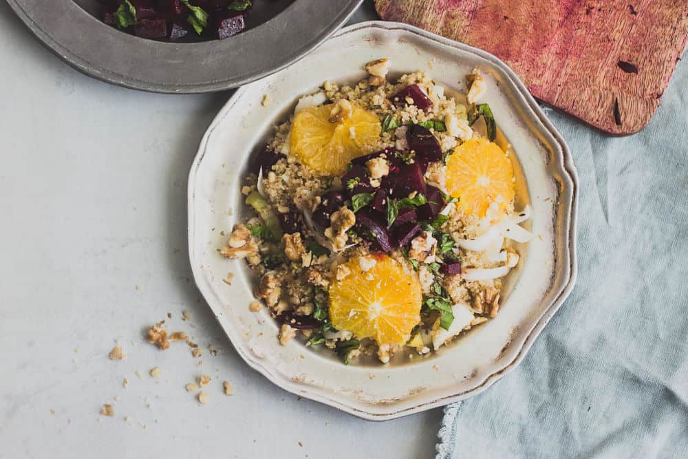 Vue de dessus de la salade de quinoa aux betteraves, oranges et noix dans une assiette métallique rustique