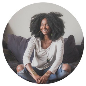 Smiling girl with big afro sitting cross-legged on a sofa