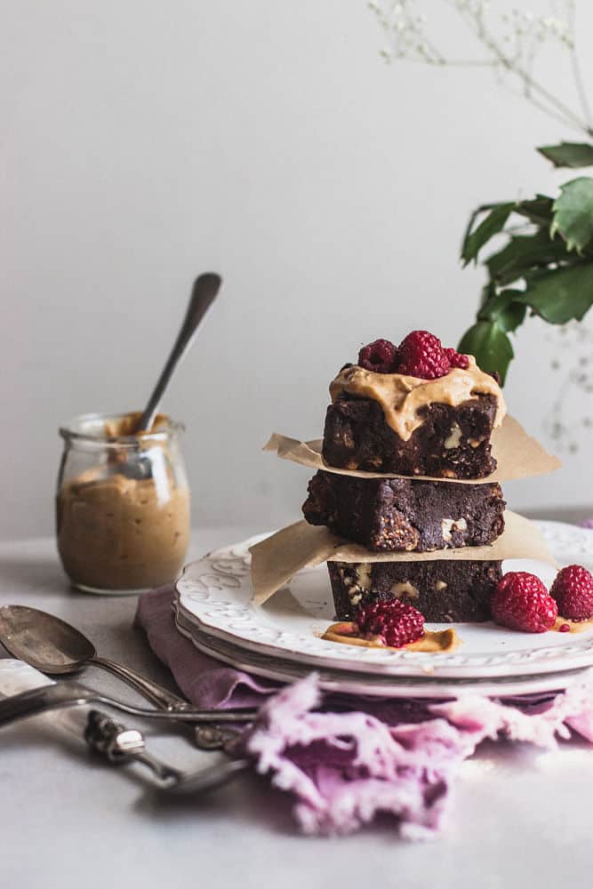 3 squared brownies stacked on each other with caramel cream and strawberries on top.