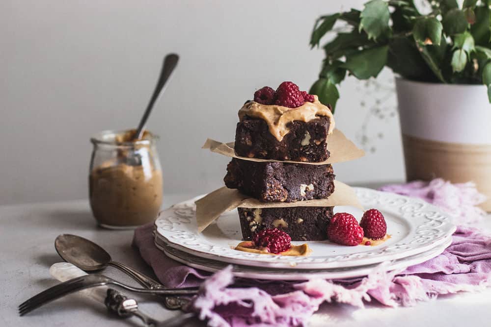 3 squared brownies stacked on each other with caramel cream and strawberries on top.