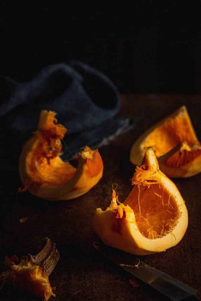 Slices of pumpkin looking like small sailboats on a brown surface