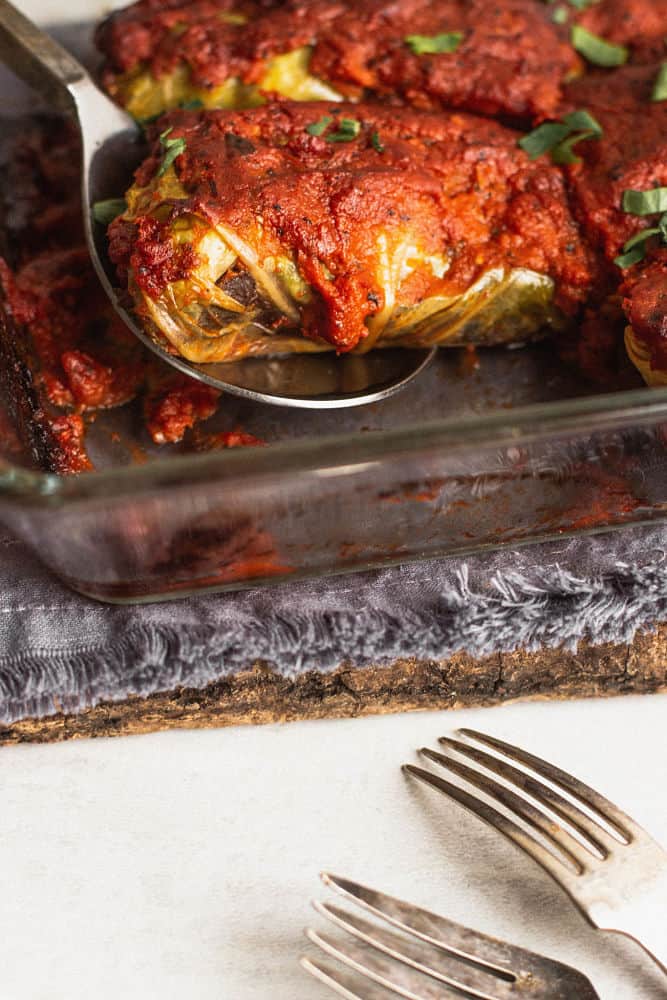 One stuffed cabbage roll with tomato sauce being lifted by a spoon