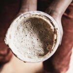 Bird's eye view of sourdough with bubbles in a small container held by two hands.