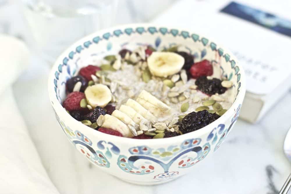 Chia pudding with sliced bananas, berries, pumpkin seeds and sunflower seeds in a colorful bowl