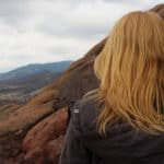 A woman back turned looking far through the mountains