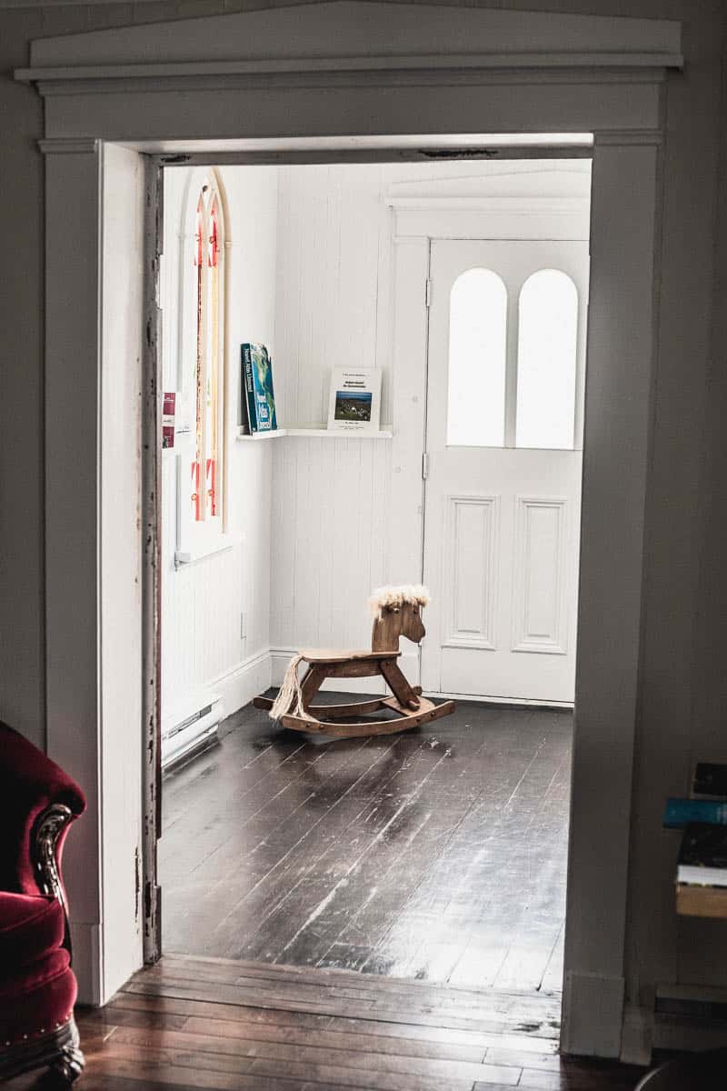 Chambre à l'Auberge Le 112, à St-André de Kamouraska, avec un cheval de bois dans le coin de la chambre sous un vitrail