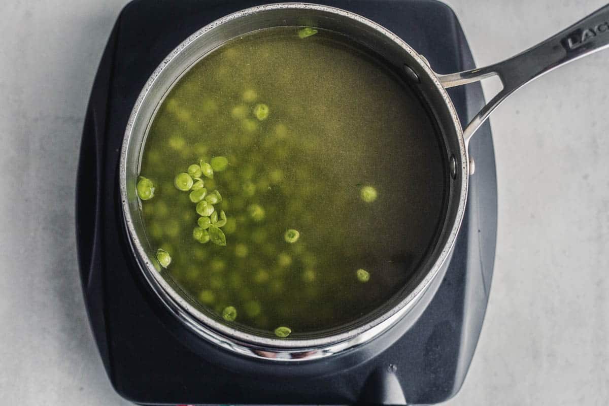 Overhead view of peas cooking in a saucepan