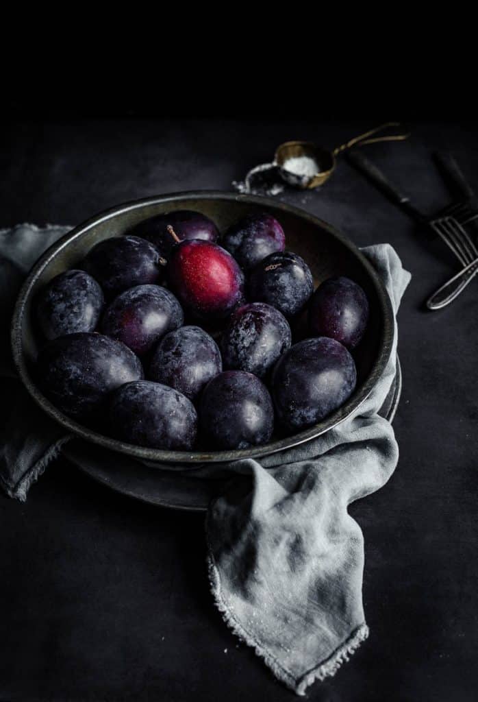 Oblong plums in a metallic plate in a dark background