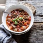 Tomato and bread soup in a bowl on a wooden board