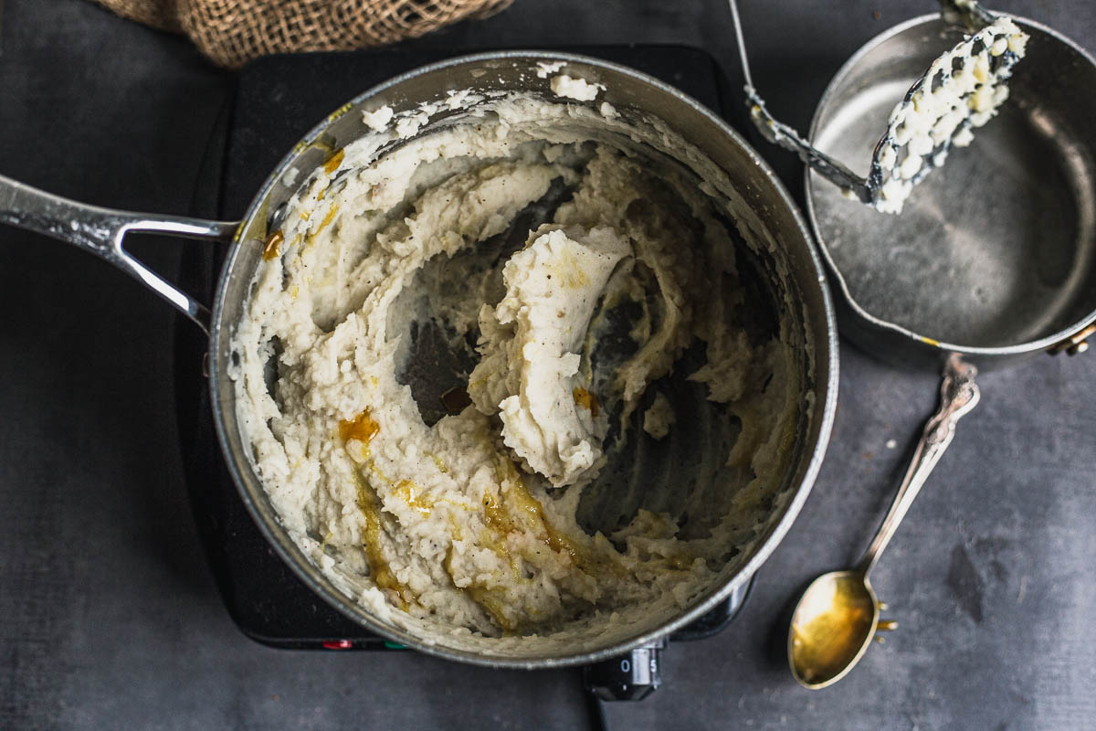 Mashed potatoes in saucepan with golden thick liquid squirted on
