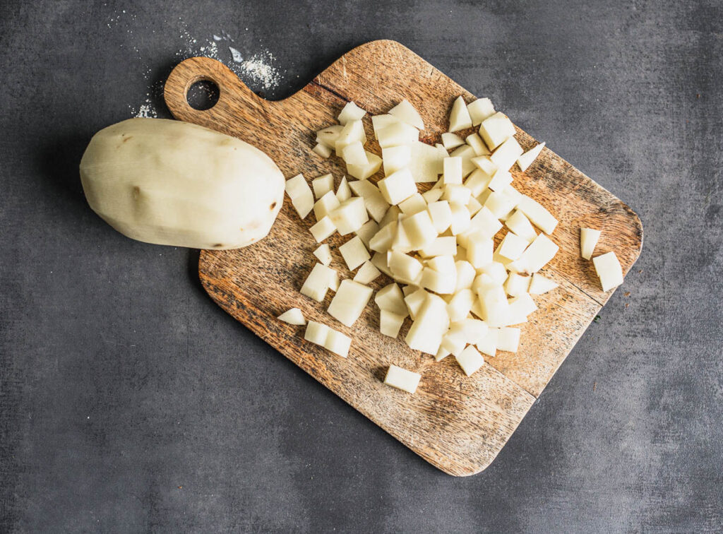 Pommes de terre coupées en cubes sur une planche à découper