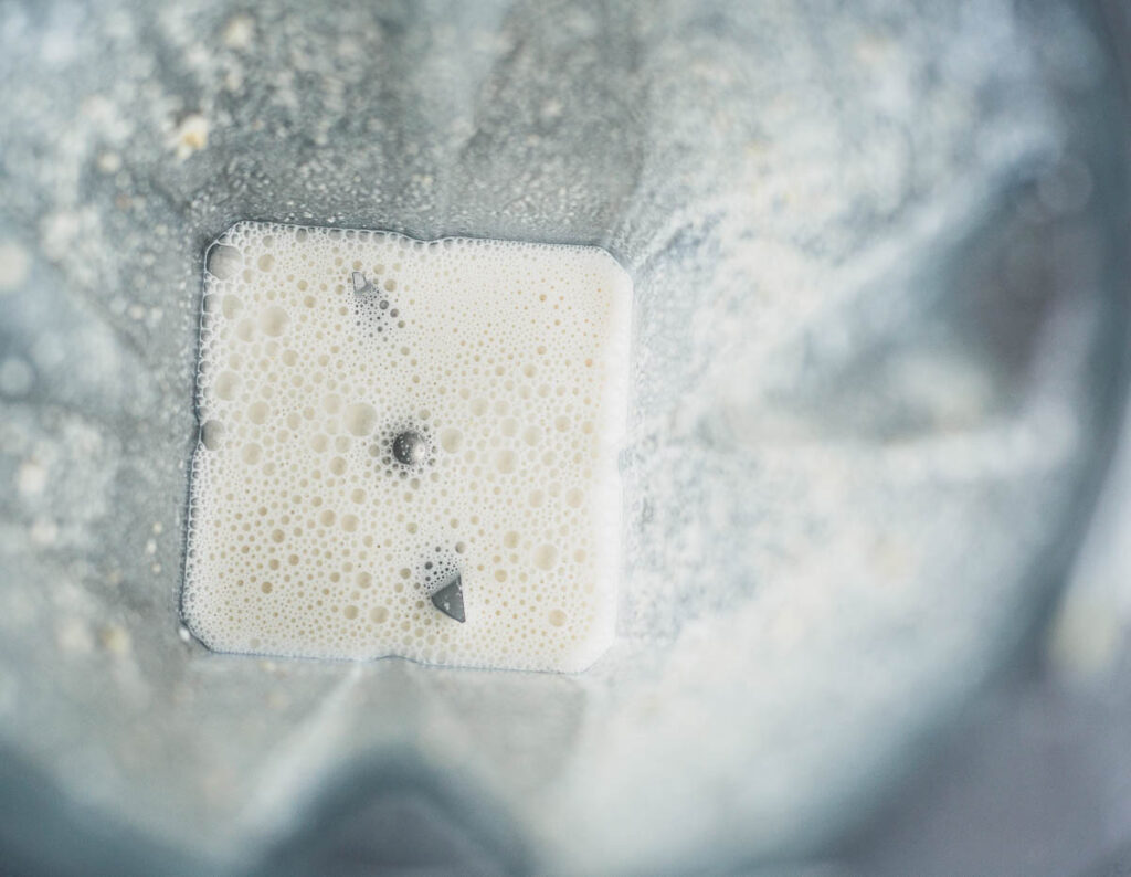 Overhead view of white milk-like liquid in blender pot