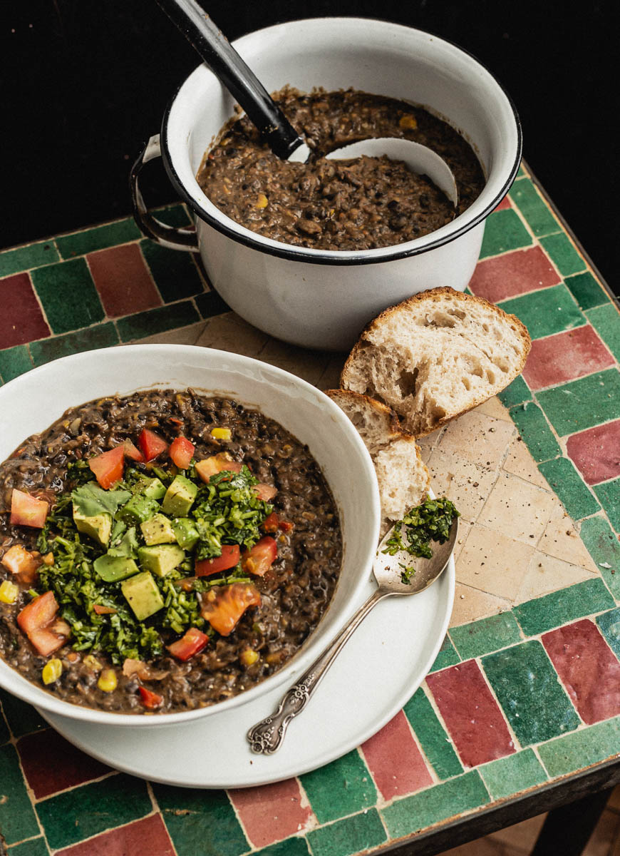 Black bean soup topped with cilantro sauce, avocado, and tomatoes