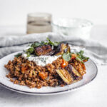 Kasha with cherry tomatoes, roasted eggplant, cream cheese style cream, mint on a plate