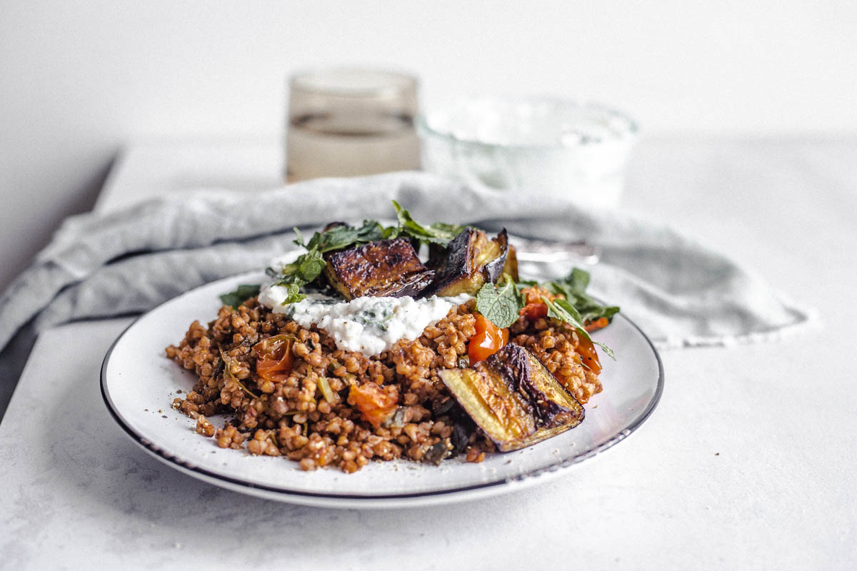 Kasha aux tomates cerises, aubergines rôties, crème façon fromage à la crème, menthe sur une assiette