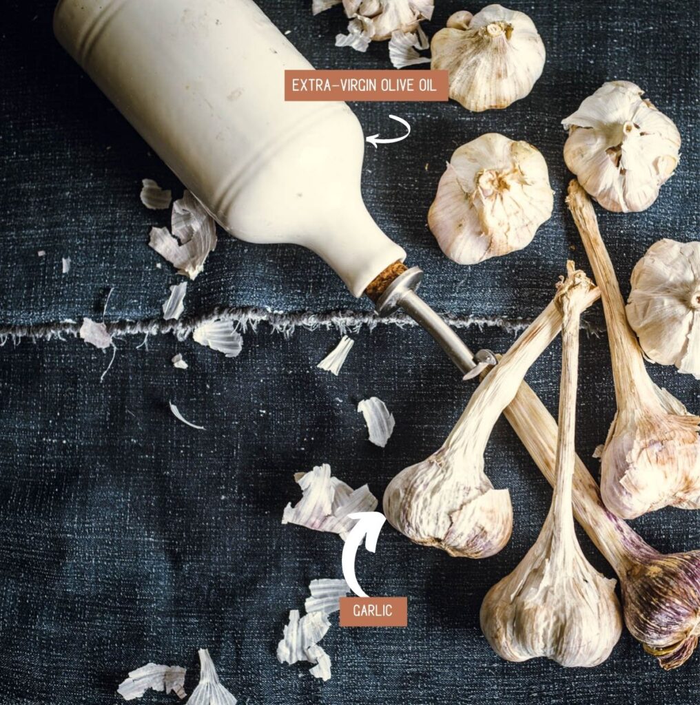 Overhead view of oil container and heads of garlic scattered decoratively