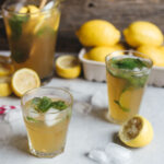 Two glasses of lemonade garnished with mint on a surface