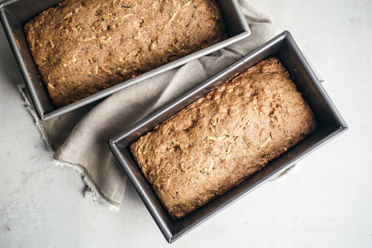 Two loaf pans with baked zucchini bread in it