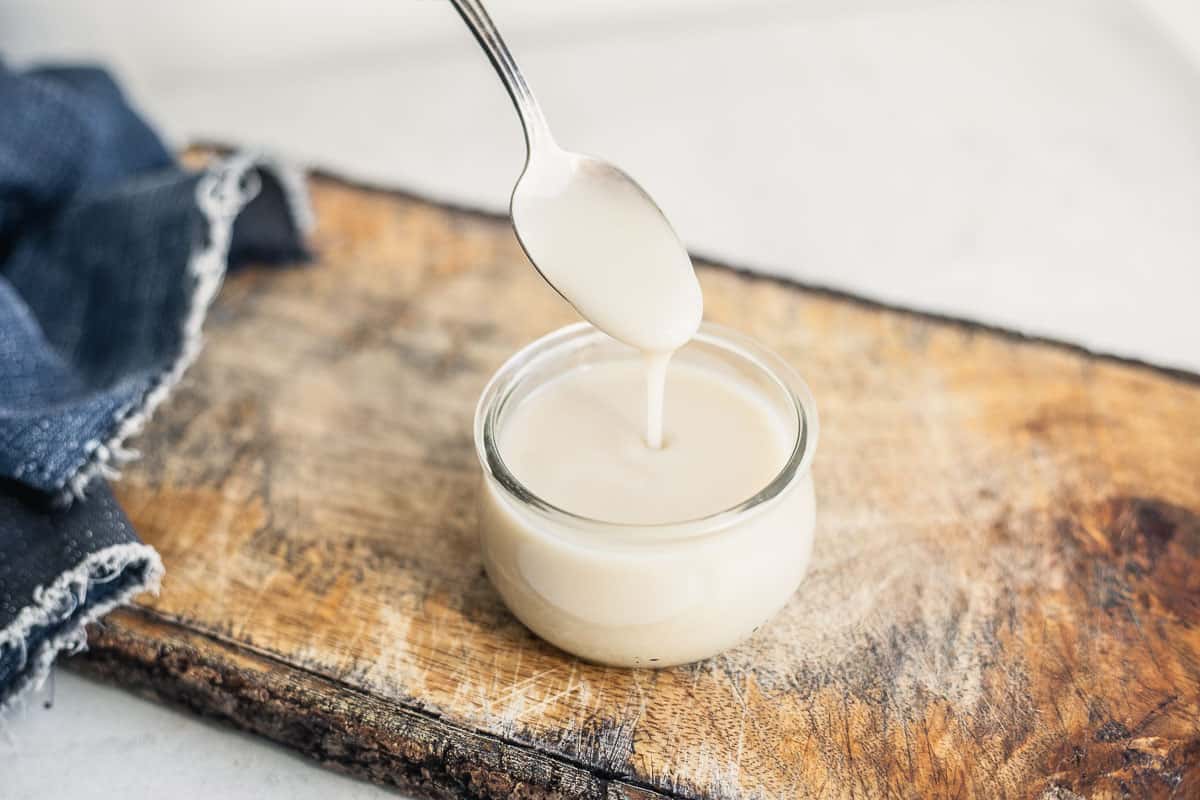 A glass jar of homemade vegan sweetened condensed coconut milk.